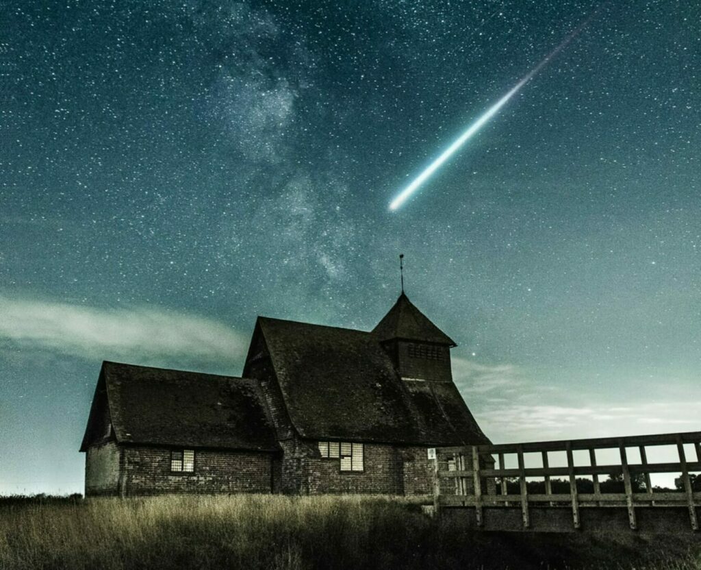 Man erkennt ein Steinhaus unter Sternenhimmel über den eine Sternschnuppe zieht